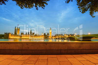 Houses of Parliament framed by trees and boardwalk at dusk - Lon