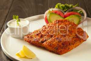 Grilled fish tikka served on a plate with salad and tarter sauce