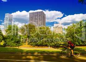 Biker riding in Central Park on a sunny summer day with Manhatta