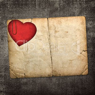 old paperboard card with red paper heart on a dark fabric backgr