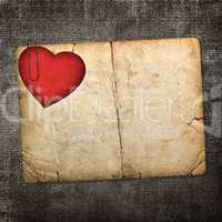 old paperboard card with red paper heart on a dark fabric backgr