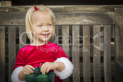 Adorable Little Girl Unwrapping Her Gift on a Bench