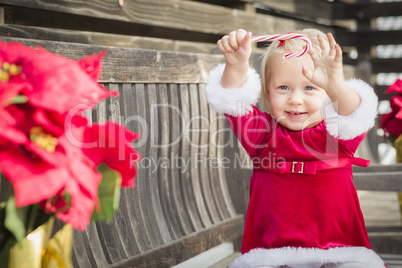 Adorable Little Girl Sitting On Bench with Her Candy Cane