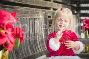 Adorable Little Girl Sitting On Bench with Her Candy Cane