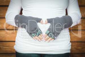 Pregnant Woman Holds Her Stomach with Love You Mittens