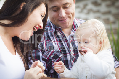 Adorable Little Girl Eating a Cookie with Mommy and Daddy