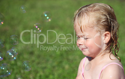 Happy little girl playing with soap bubbles in the garden