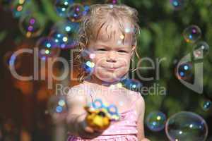 Happy little girl playing with soap bubbles in the garden