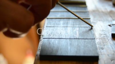 Luthier makes the frets of a guitar