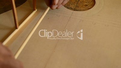 Luthier puts a rod in the harmonic cover of a guitar