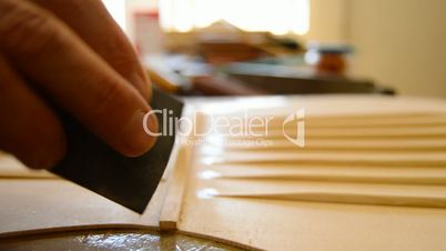 Luthier sanding a guitar in close up, pan