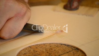 Luthier working with chisel manufacturing a guitar