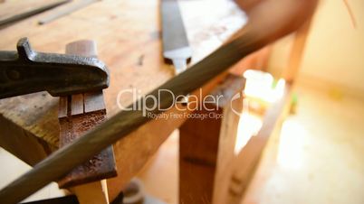 Close up of luthier sanding a guitar piece in workplace