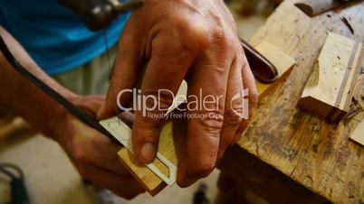 Luthier cutting a guitar piece with a hacksaw