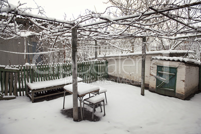 snowy rural courtyard with homemade table, chairs and bench