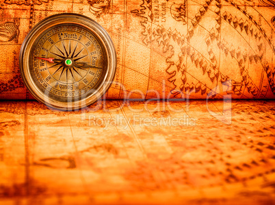 Vintage compass lies on an ancient world map.