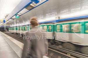 Blurred picture of moving business man in Paris Metro with train