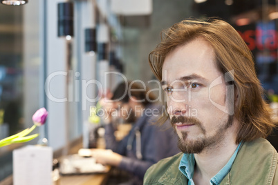 Portrait of a pensive and handsome young man in coffee shop