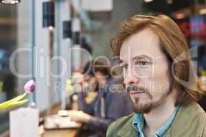 Portrait of a pensive and handsome young man in coffee shop