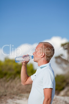 young man ist drinking water summertime dune beach sky
