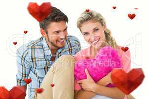 Composite image of attractive young couple sitting holding heart