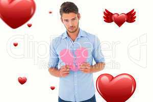 Composite image of sad man holding a broken heart