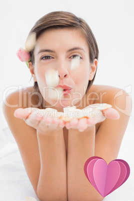 Composite image of beautiful happy woman blowing flower petals a