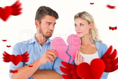 Composite image of couple holding two halves of broken heart