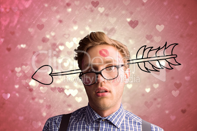 Composite image of geeky hipster covered in kisses