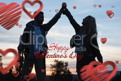 Composite image of silhouette couple holding up hands at dusk