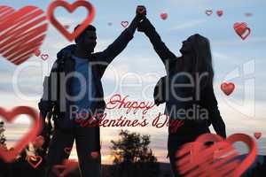Composite image of silhouette couple holding up hands at dusk