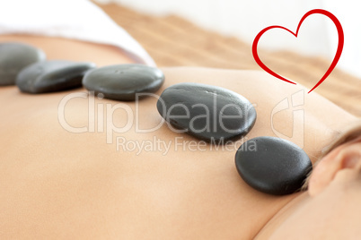 Composite image of close up of a woman with hot stones on her ba