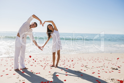 Composite image of loving couple forming heart shape with arms