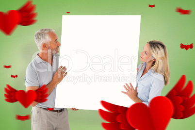 Composite image of happy couple holding large poster