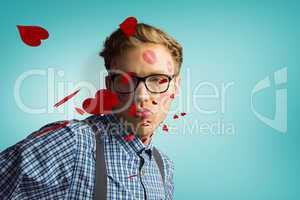 Composite image of geeky hipster covered in kisses