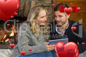 Composite image of couple using tablet pc in front of lit firepl