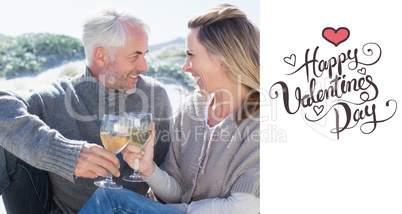 Composite image of couple enjoying white wine on picnic at the b