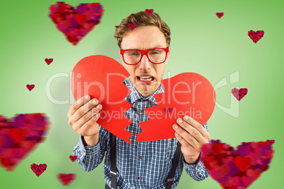 Composite image of geeky hipster holding a broken heart