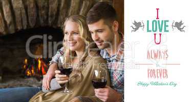 Composite image of couple with wineglasses in front of lit firep