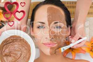 Composite image of peaceful brunette getting a mud facial applie