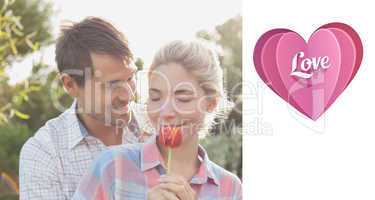 Composite image of young couple holding a flower in park