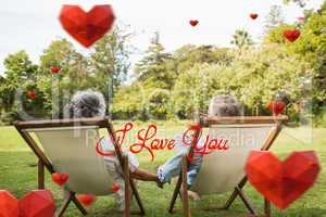 Composite image of happy mature couple sitting in park