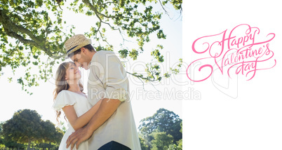 Composite image of cute couple standing in the park embracing