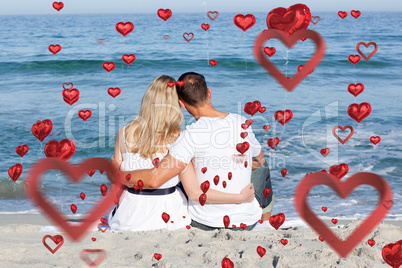 Composite image of affectionate couple sitting on the sand at th