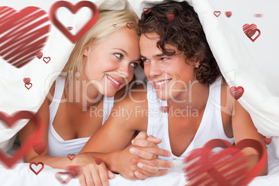 Composite image of portrait of an in love couple under a duvet