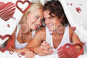 Composite image of portrait of an in love couple under a duvet