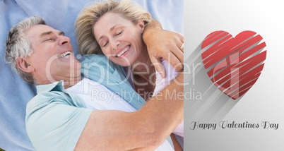 Composite image of happy senior couple cuddling on blanket