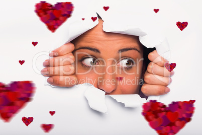 Composite image of young woman looking through paper rip