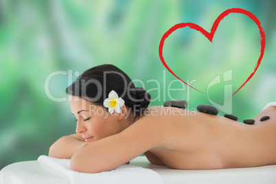 Composite image of beautiful brunette relaxing on massage table