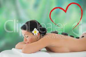 Composite image of beautiful brunette relaxing on massage table
